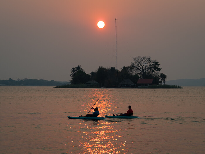 two men kayaking on Lake Peten Itza with the setting sun in the background