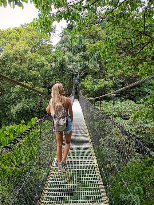 A woman standing on a hanging bridge surrounded by tropical vegetation at Mistico Hanging Bridges Park in Costa Rica