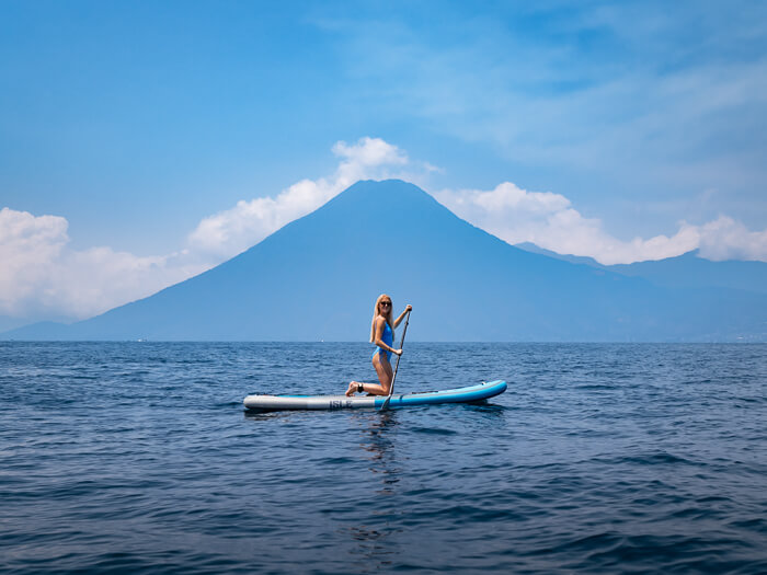 A woman stand up paddling on Lake Atitlan with a backdrop of San Pedro volcano