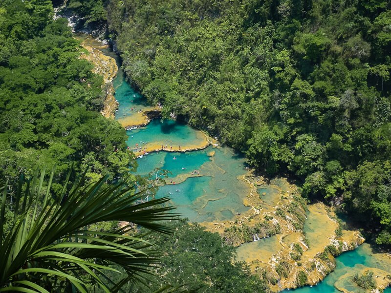 a series of bright blue natural pools surrounded by lush greenery at Semuc Champey