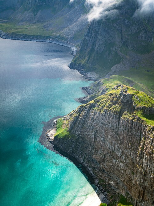A steep cliff rising out of turquoise sea, a mesmerizing view along the Håen hike.