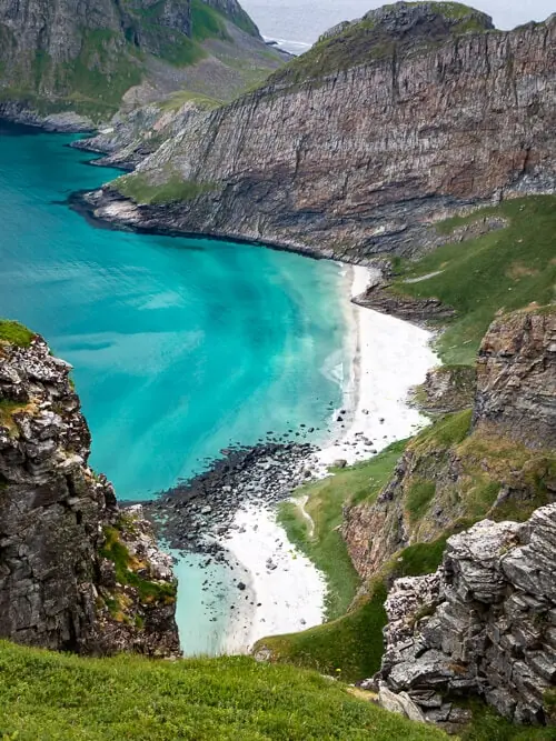 vibrant blue water and white sand at the secluded Puinn Sand Beach nestled between steep mountains on Værøy island