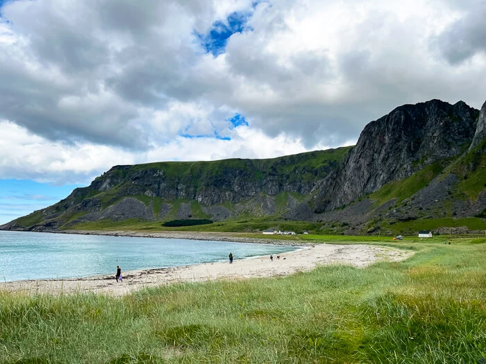 Green meadow and jagged mountains around Unstad Beach, the most famous surf beach on the Lofoten Islands