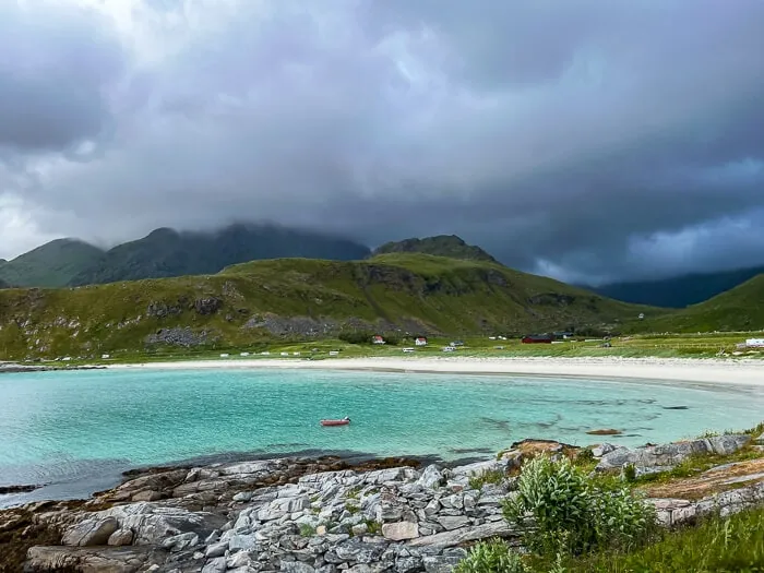 Bright turquoise water, a crescent of white sand and dark cloudy sky at Vik Beach