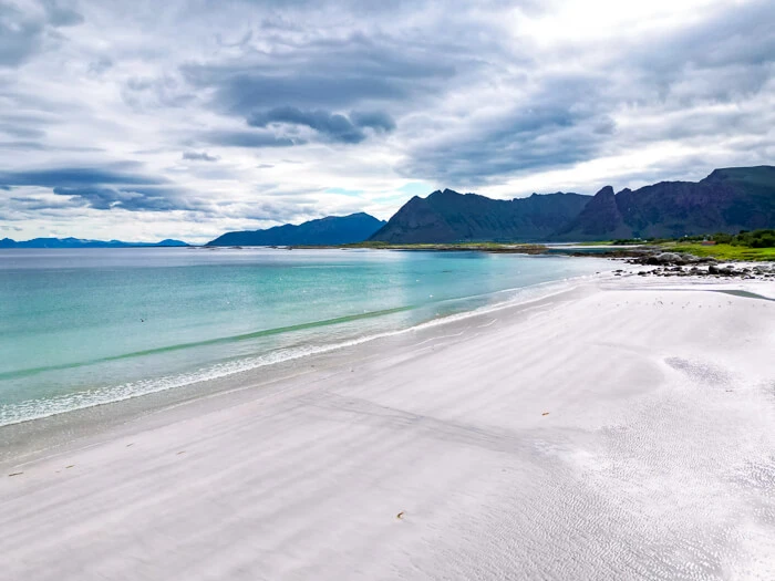 A large stretch of bright white sand and calm turquoise sea at Gimsøy Beach in Lofoten