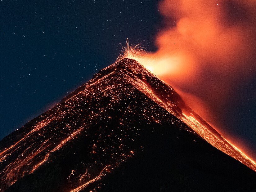 A volcano erupting with bright orange lava pouring down its sides