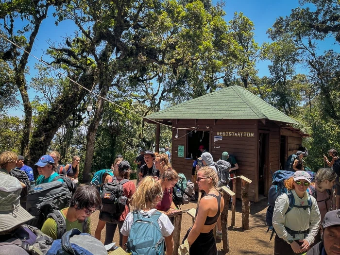 a large group of hikers waiting next to a wooden hut at Acatenango National Park entrance