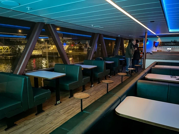 Seats, tables and a bar in the salon of Brim Explorer's whale tour catamaran