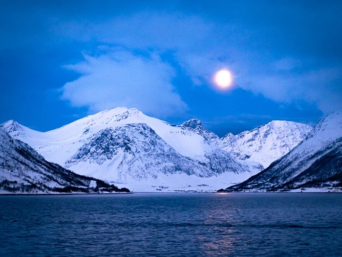 A bright full moon illuminating snow-capped mountains during a Polar Night in northen Norway