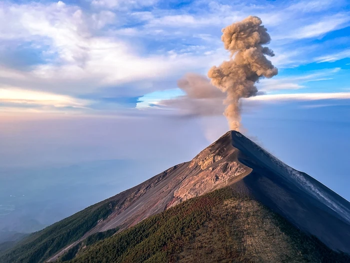 a volcano spitting out a plume of smoke during sunrise; one of the best views on the Acatenango hike