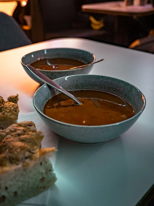 two bowls of tomato soup and some bread