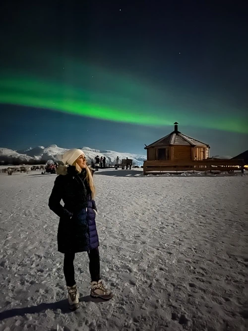 Me admiring the vivid green Northern Lights amidst snowy landscapes near Tromso, Norway