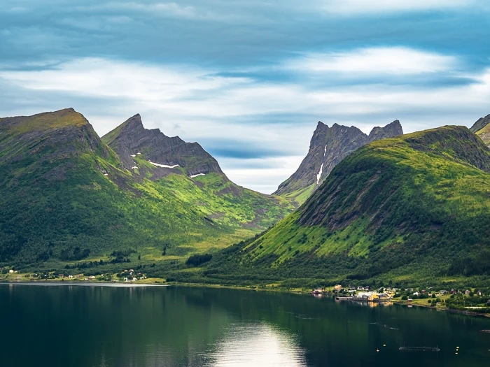 mountains with jagged granite peaks and green slopes next to a fjord at Bergsbotn, a must-see spot when visiting Senja, Norway