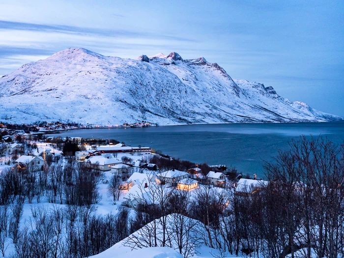 Snowy mountains and a small village around the scenic Ersfjord, a perfect destination to visit on a road trip from Tromso