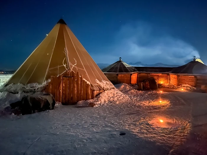 A cone-shaped Sami tent and a pathway lit up by candles leading to the Sami camp