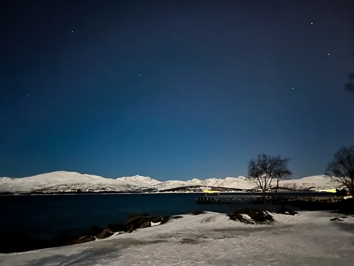Snowy scenery and starry sky on a clear night at Telegrafbukta beach, one of the best spots to see Northern Lights in Tromso town