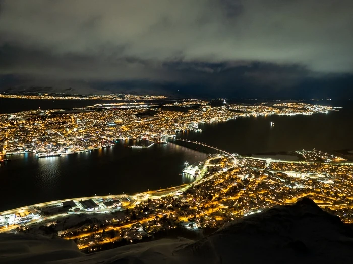 A panoramic nighttime view of the city of Tromso viewed from Storsteinen mountain, a must-visit spot on any Tromso itinerary