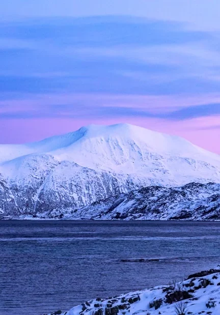 A snow-covered mountain with a backdrop of pink and purple sky near Tromso, Norway