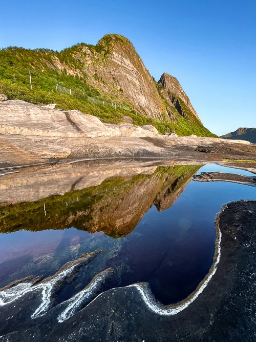 A reflection of a mountain on a puddle of water at Tungeneset rest area, one of the best places to visit in Senja 