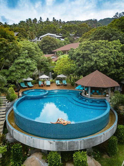 Me lying on the edge of a large round pool surrounded by jungle at Ban's Diving Resort