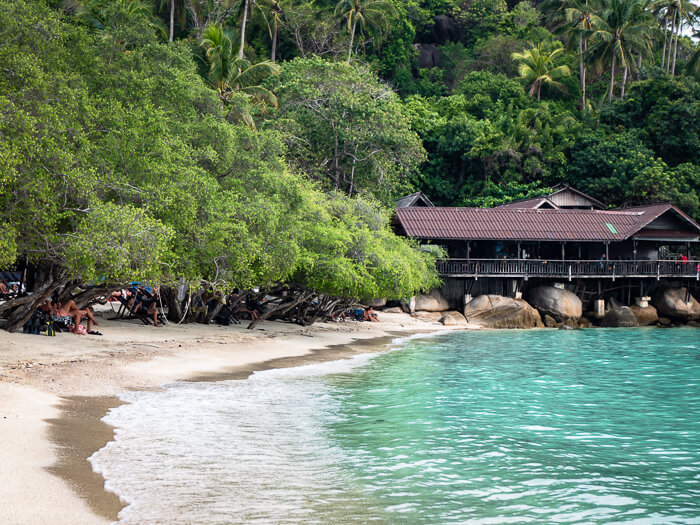 Calm blue water and a stretch of white sand lined with small trees at Freedom Beach.