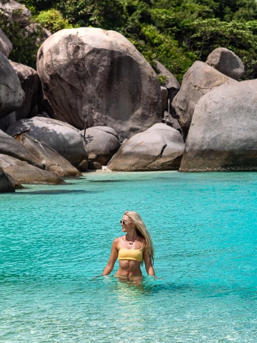 Me standing waist-deep in clear blue water with large grey boulders in the background at Koh Nang Yuan Beach.