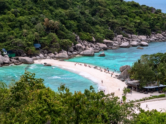 A narrow white sandbank at Koh Nang Yuan Island, surrounded by turquoise water and hills covered with green vegetation.