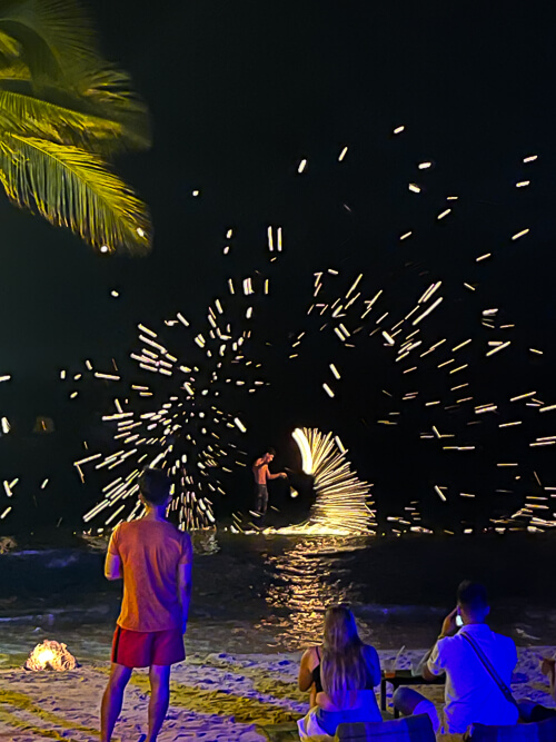 People watching a fire show performer on Sairee Beach at night.