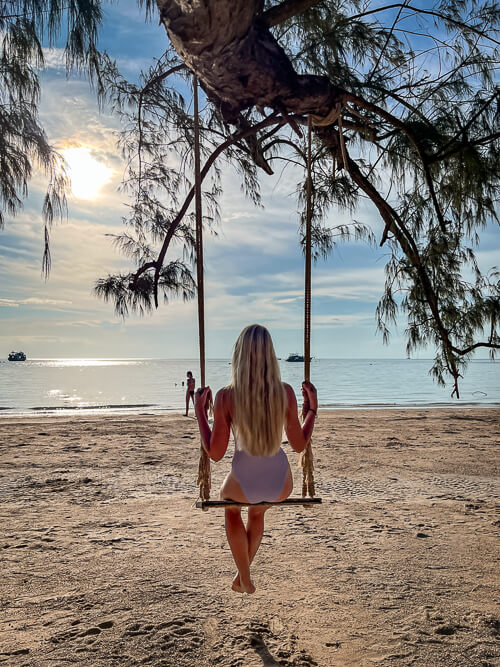 Me sitting on a swing hanging from a tree on a beach and gazing at the sea.