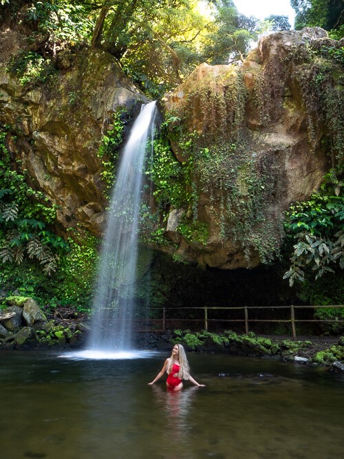 Me standing in the natural pool in front of Cascata da Gruta waterfall, one of the best Azores waterfalls.