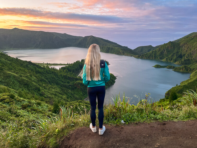 Me admiring the view over the Lagoa do Fogo lake during sunrise with colorful sky in the background.