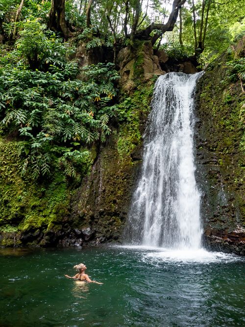 Me swimming in the plunge pool of Salto do Prego waterfall in the middle of lush vegetation and mossy rocks.