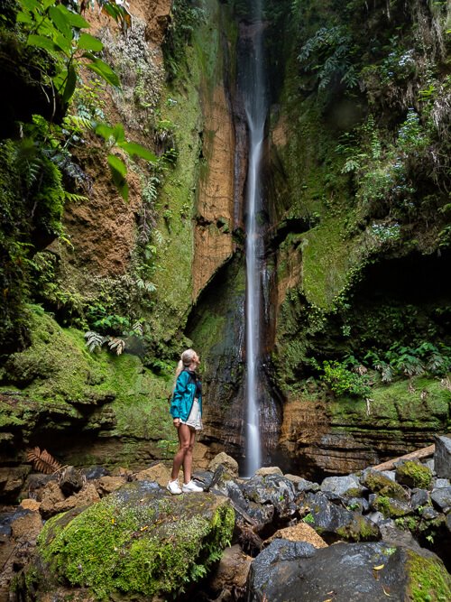 Me standing on a big rock and looking at the thin stream of water of Salto do Rosal in a narrow green canyon near Furnas.