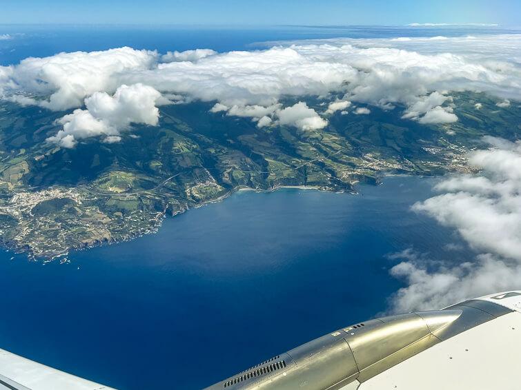 An aerial view of the south coast and the green interior of Sao Miguel Island viewed from the window of an airplane.