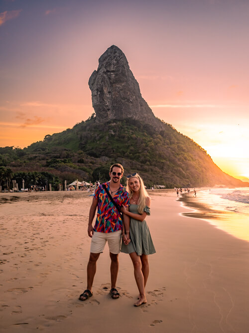 Me and my husband posing with the Morro do Pico mountain on Conceição Beach, one of the best sunset spots in Fernando de Noronha.