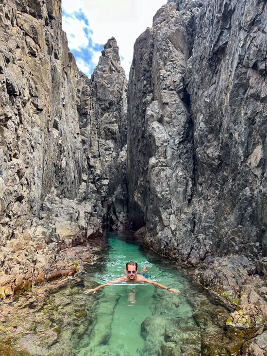 My husband swimming in a narrow natural pool between vertical rocks, known as Lasca da Velha.