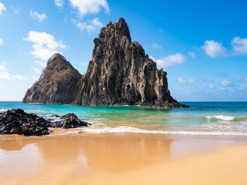 Two large volcanic formations standing vertically in the turquoise sea near Cacimba do Padre Beach in Fernando de Noronha.