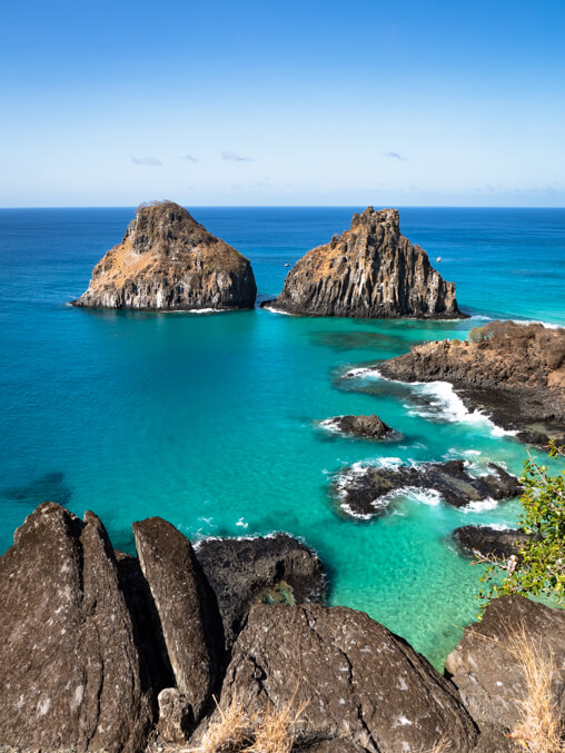 The two Morro Dois Irmaos rock formations surrounded by turquosie ocean, a must-visit place in Fernando de Noronha.