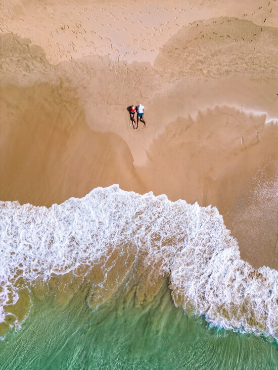 A top-down drone shot of my husband and I lying in the sand on Boldro Beach.