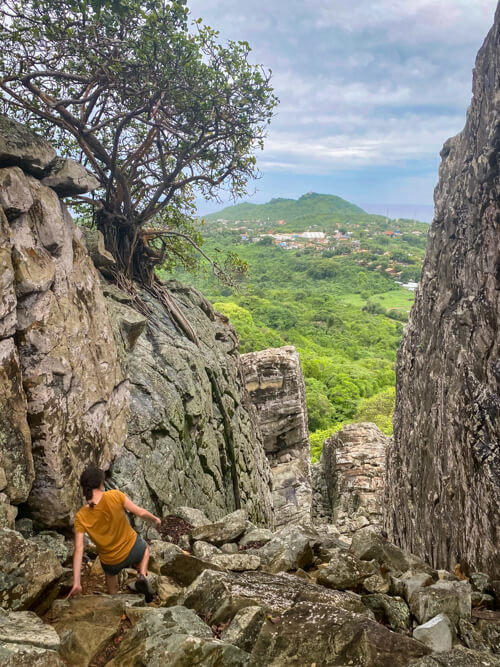 A woman hiking down a mountainside covered with large rocks on the Piquinho trail.