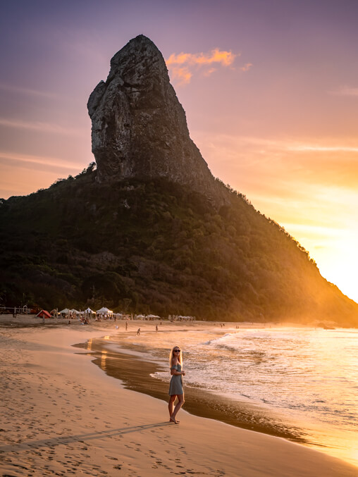 Me standing on Conceição Beach with Morro do Pico in the background during sunset.
