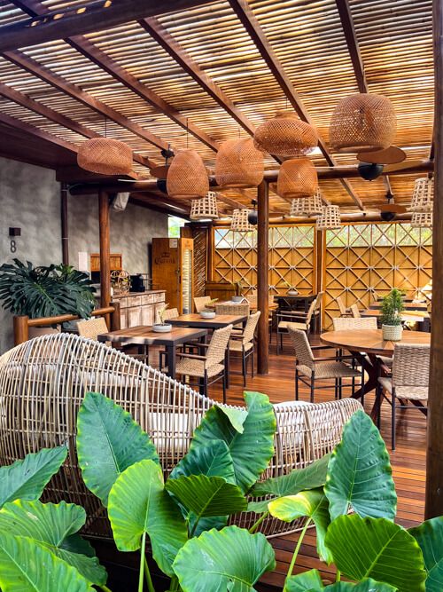 A dining area decorated in boho style and surrounded by lush plants at Vila Sal Noronha.
