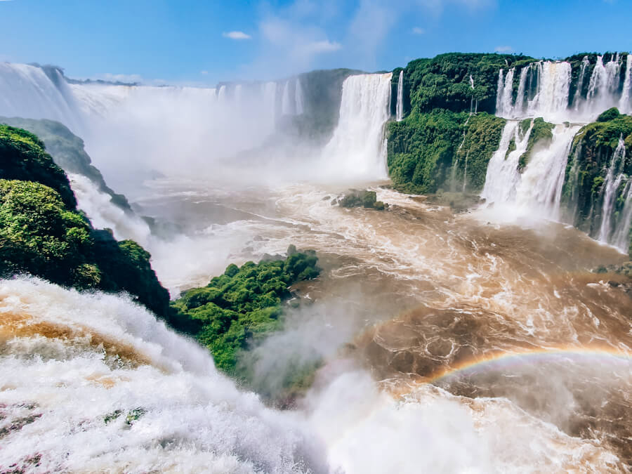 A view of a series of misty waterfalls surrounded by lush tropical vegetation at Iguazu Falls.