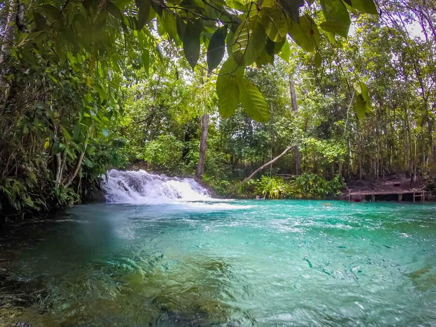 A small waterfall and a natural pool full of clear blue water surrounded by forest at Jalapao, a hidden gem in Brazil.