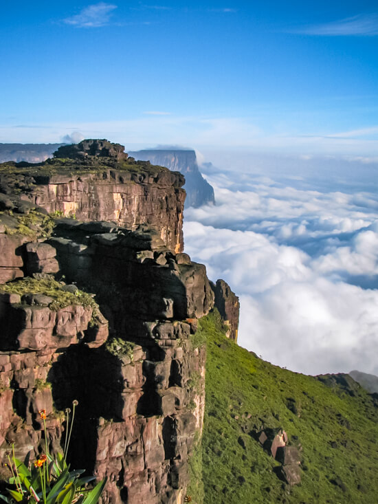 The rocky summit of Mount Roraima with its vertical slopes and a flat top towering high above the clouds.