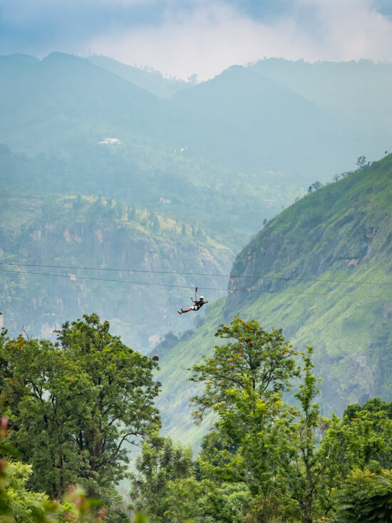 A man riding a zipline with mountainous scenery in the background, one of the best things to do in Ella for thrill-seekers.
