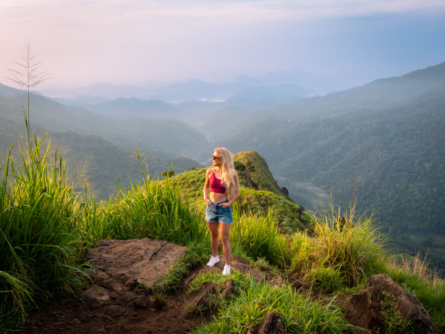 Me standing on top of Little Adam's Peak during sunrise with a panoramic view of mountains in the background.