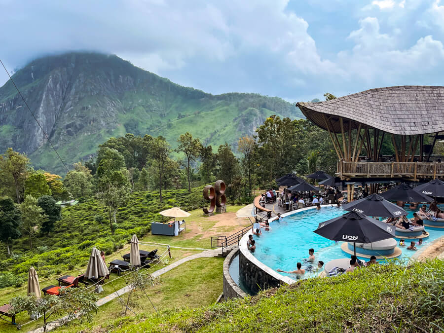The infinity pool and garden of Ravana Pool Club overlooking a mountainous landscape.