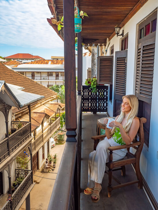 Me sitting and drinking my morning coffee on our balcony overlooking a street at Dhow Palace Hotel.