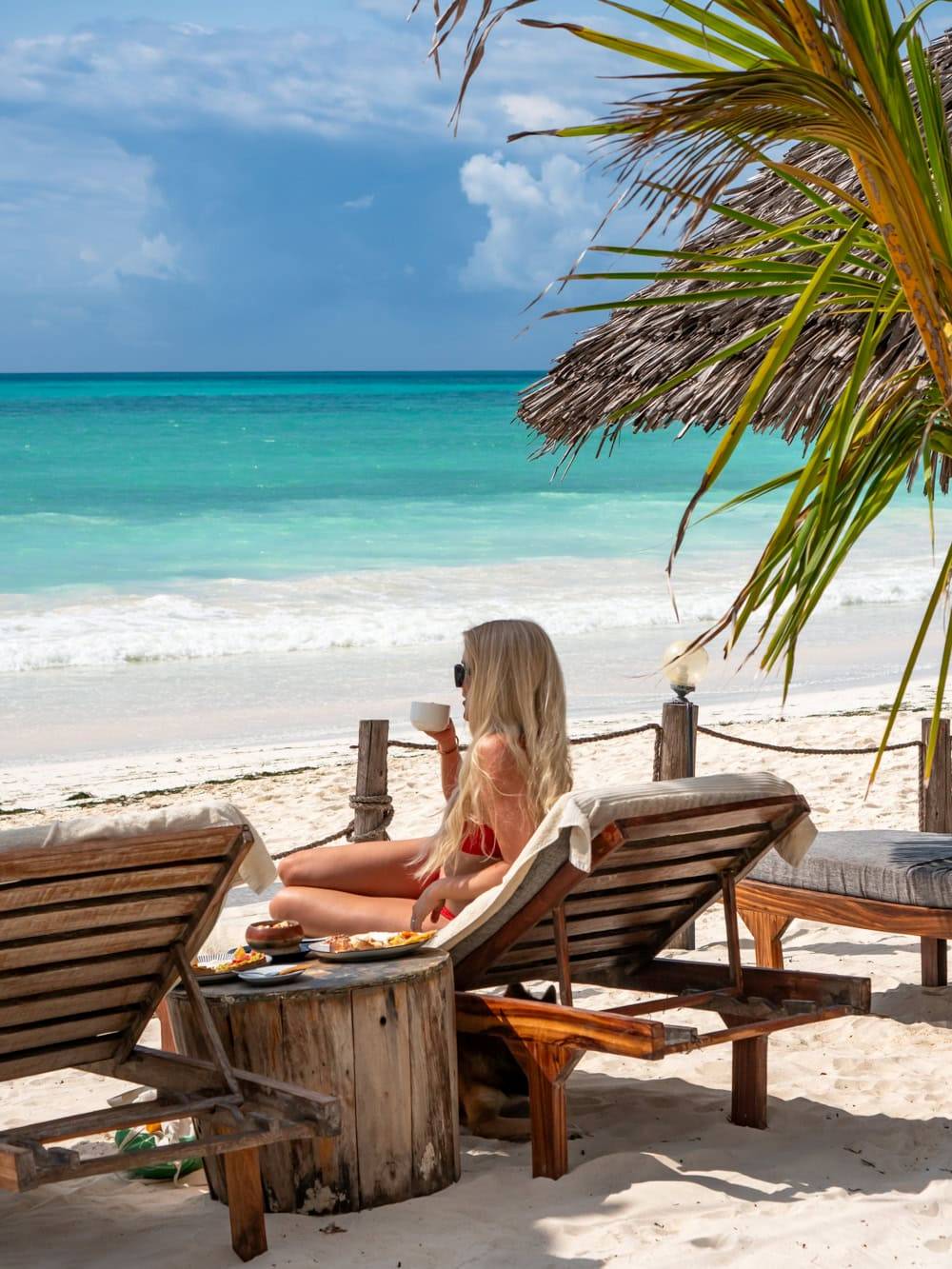 Me lying on a sunbed and drinking a cup of coffee with a view of turquoise ocean at Paje Beach.